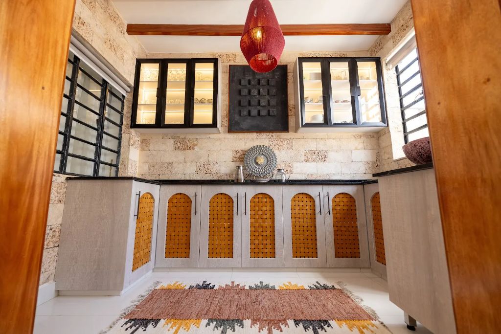 Arched rattan-fronted cabinetry beneath black granite counters