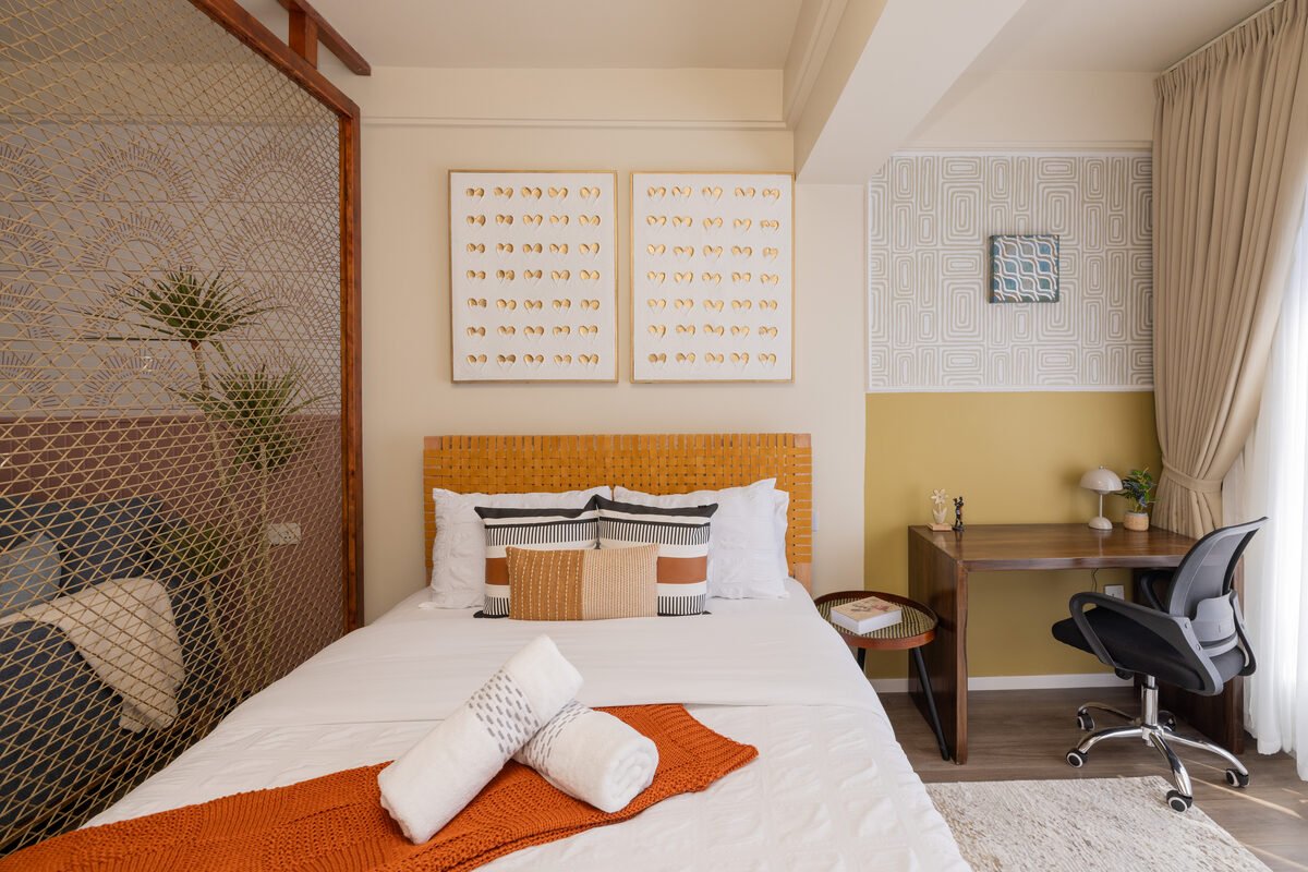 Bedroom nook with woven rattan headboard, framed textural art and mustard accent wall