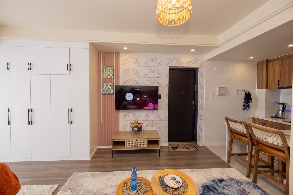 Built-in white wardrobes and wall-mounted TV against sunburst wallpaper