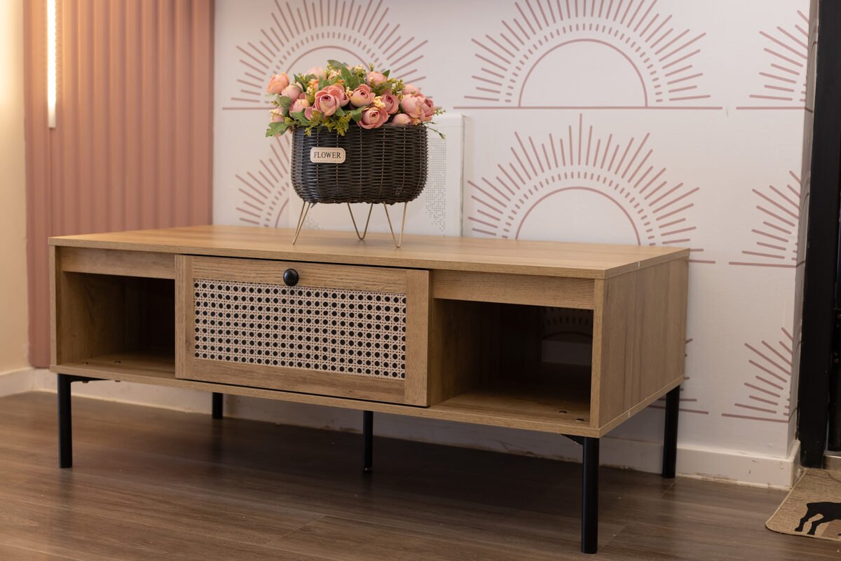Cane-fronted TV console against sunburst wallpaper near the entry door