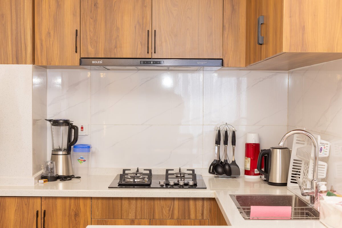 Wood kitchen cabinetry with marble-look splashback and black cooker hood