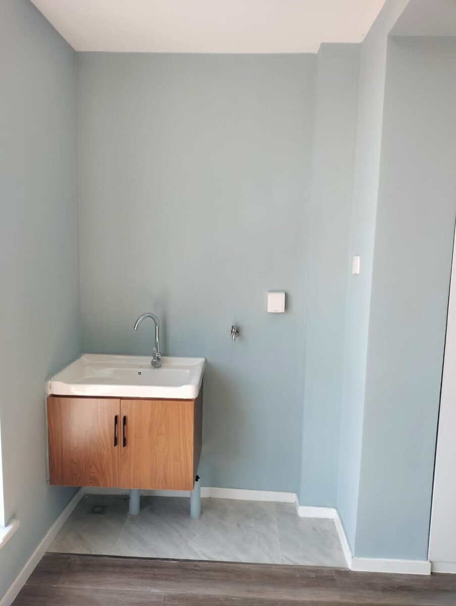 Before: bare blue-gray bathroom walls with a basic wall-mounted vanity