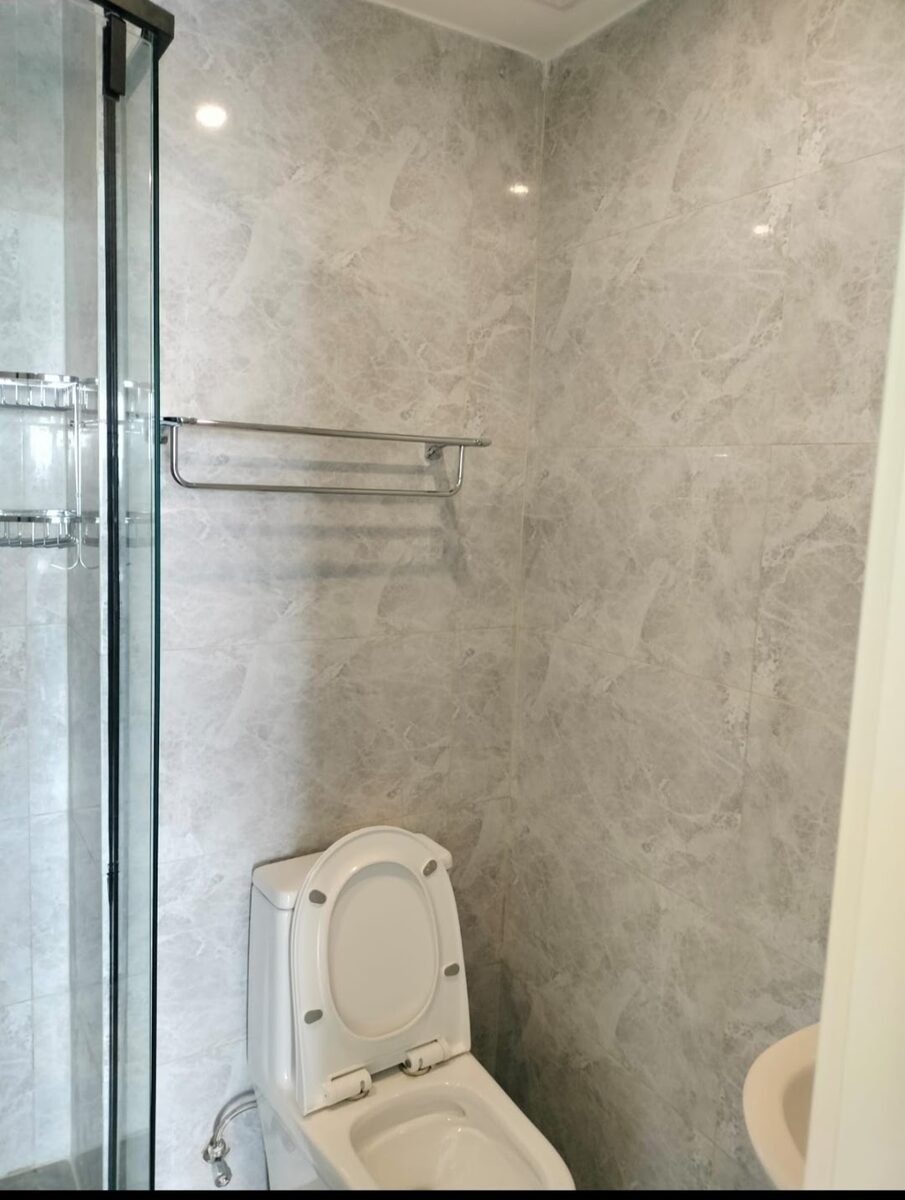 Before: gray marble-effect tile shower area with chrome towel rail