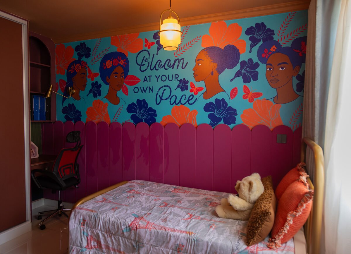 Pre-teen girl's bedroom with custom teal mural and gold-frame bed