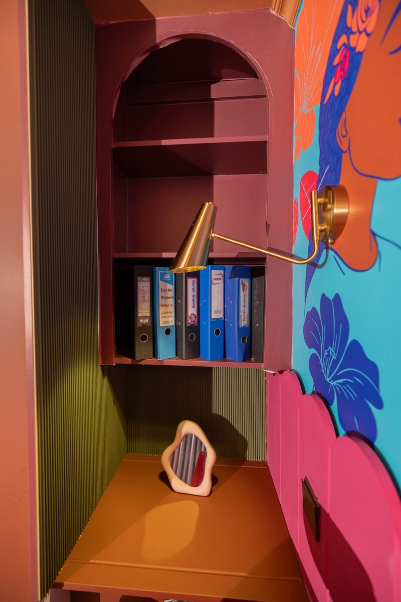 Arched built-in desk nook with labelled file binders and a brass gooseneck wall lamp