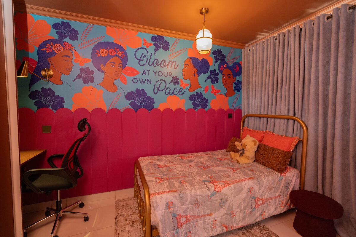 Gold-frame bed against the mural wall with a gray curtain and round ottoman