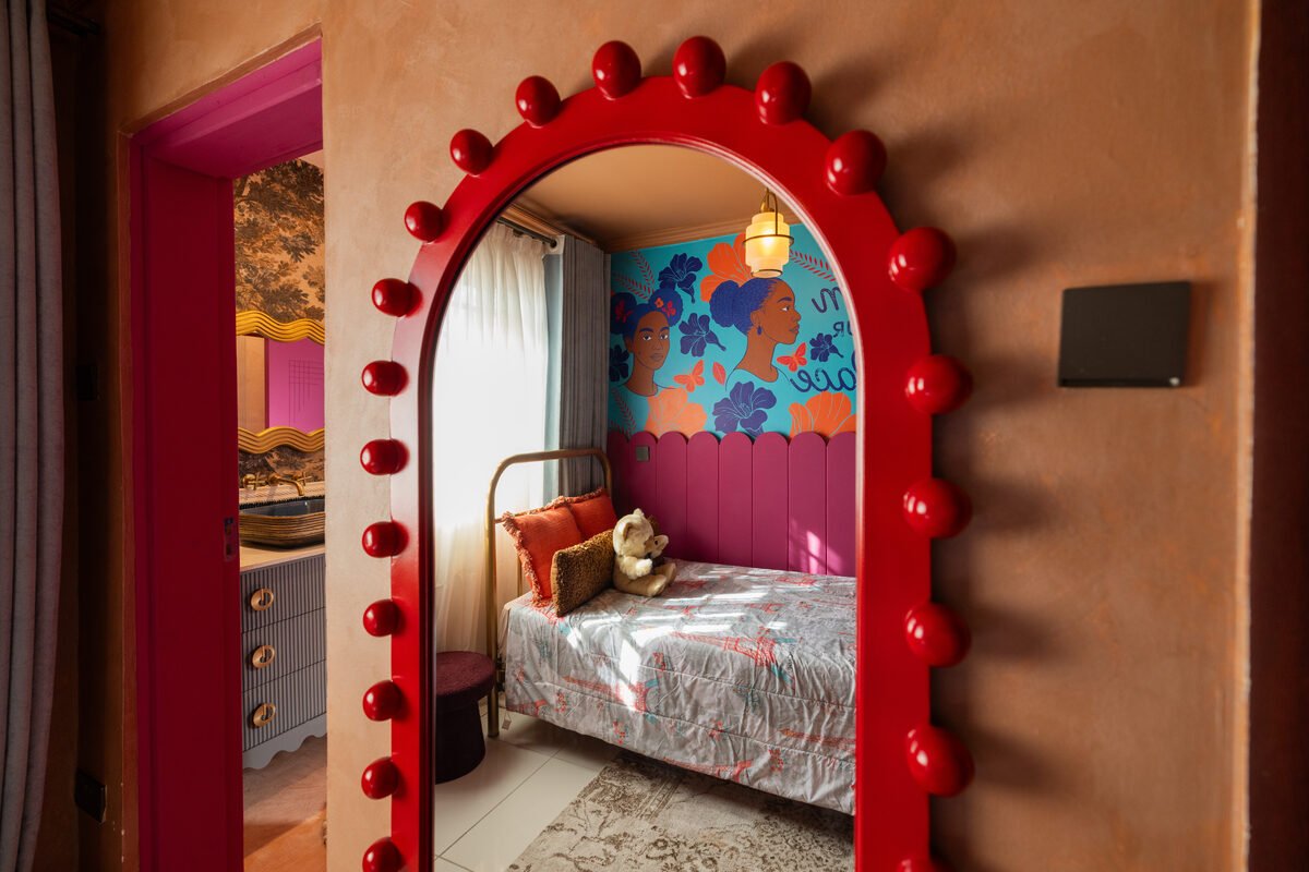 Rectangular mirror with red pom-pom trim in the hallway reflecting the mural bedroom