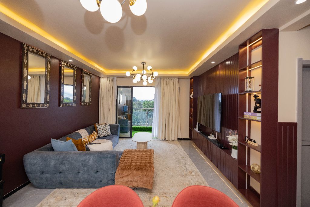 Living room with mirrored wall and warm burgundy accents, Nairobi family residence — Yaara Design Studio