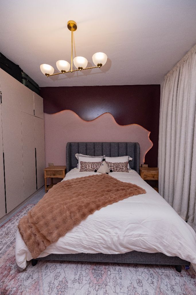 Primary bedroom with sculpted wall detail and brass chandelier, Nairobi family residence